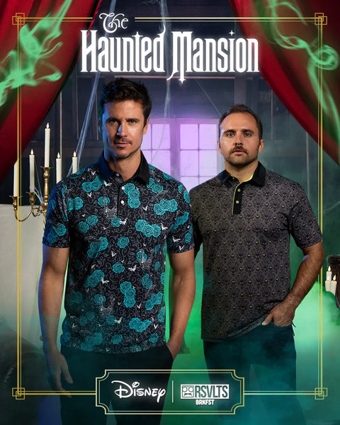 two-men-standing-in-a-theatrical-style-promotional-scene-for-disneys-the-haunted-mansion-wearing-brkfst-polos-with-red-curtains-green-smoke-and-dark-patterned-shirts-disney-and-rsvlts-brands-logos-appear-at-the-bottom